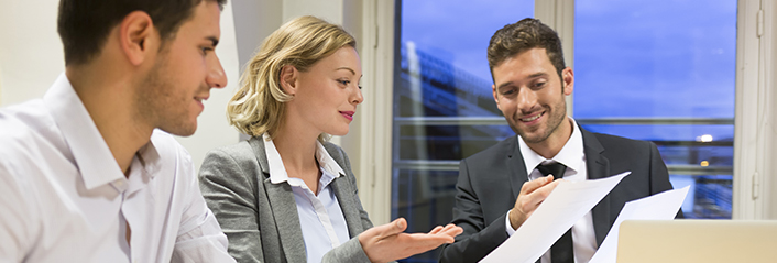 Three business people look over documents together.